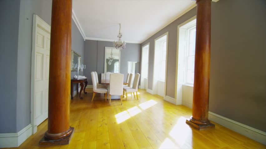 View of elegant dining room and living area in a stylish, classically designed home with large windows and lots of natural light. No people.