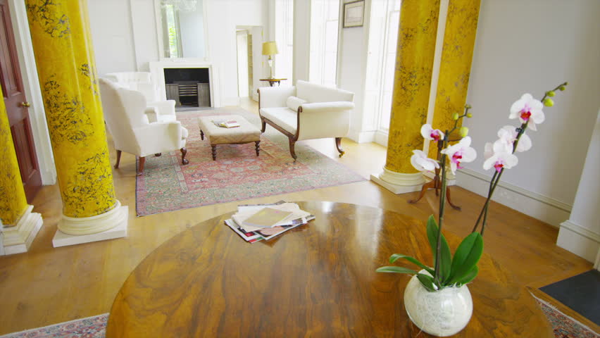 Mature man in elegant home sits down to relax and read a newspaper.