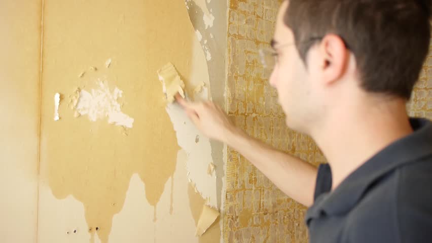 Contractor working to remove the wallpaper on a wall