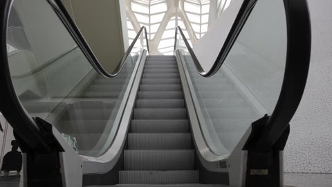 Escalator with grey stairs moving down in empty hall