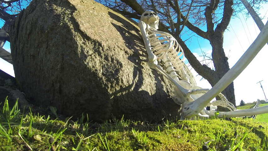 Skeleton HIllside Color 3a. Skeleton resting on a picturesque country hillside. Tilting up. Shot in time lapse. Rendered in UltraHD 4K from high resolution stills.