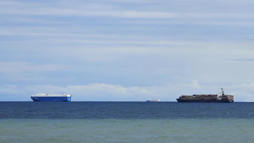 Three cargo ships out at sea. 