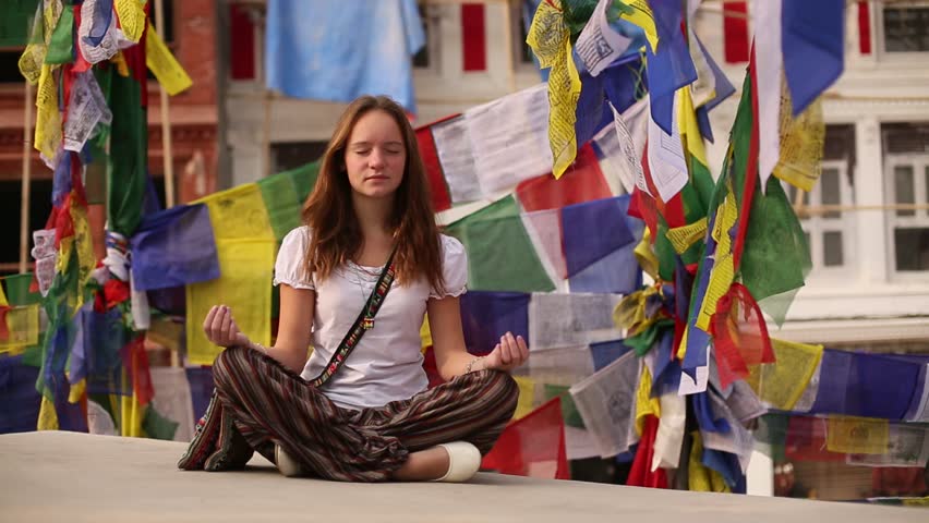 Yoga girl meditating in Lotos pose circle stupa Boudhanath in Kathmandu, Nepal -