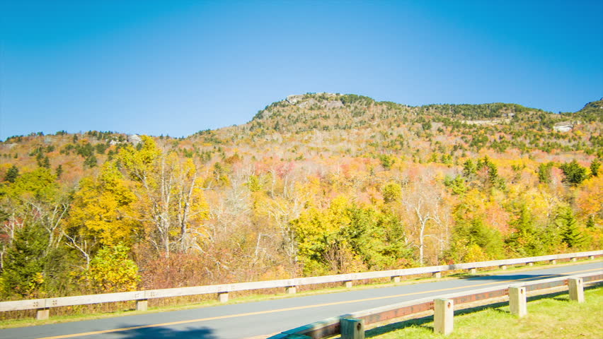 A Camper Driving on the Blue Ridge Parkway against Grandfather Mountain near Linville, NC on a a Sunny Day in the Fall with Autumn Colored Leaves and a Blue Sky.