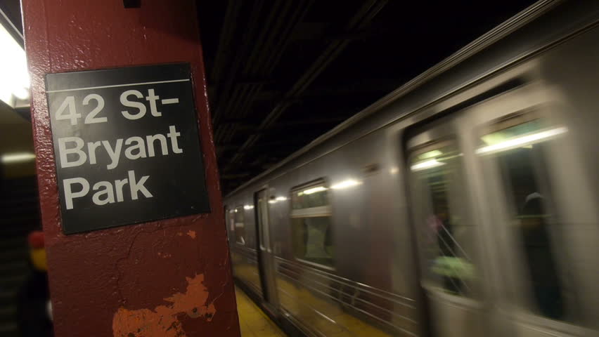 Passengers wait as a New York City subway approaches the platform.
