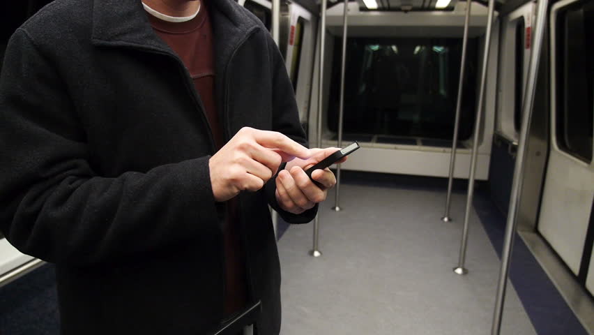 A man uses his smartphone on the subway.