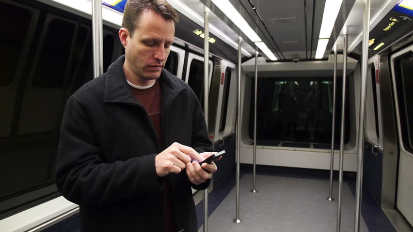 A man uses his smartphone on the subway.