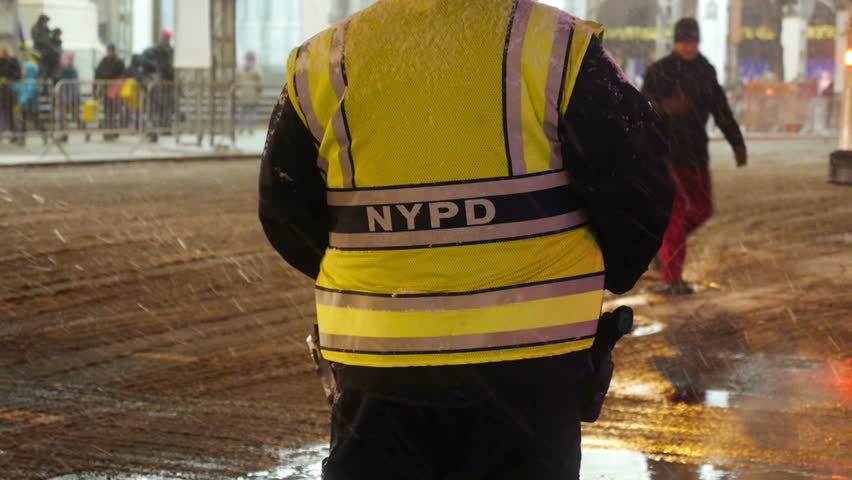 A New York City police officer helps guide traffic and pedestrians on the snowy