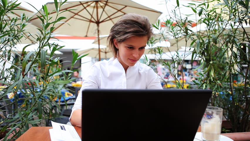 Young businesswoman with laptop in outdoor cafe