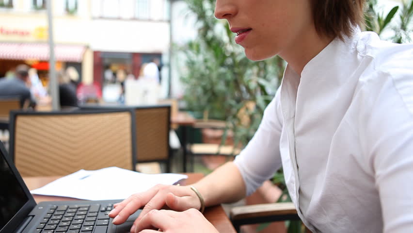 Young businesswoman with laptop in outdoor cafe