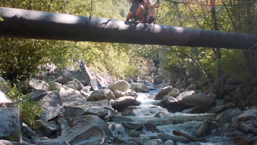 Teenage Girls Walking, Hopping Across A Forest Walk Bridge