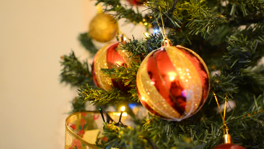 Putting colorful ball ornament on Christmas tree, closeup