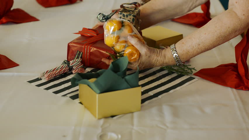 Hands of an elderly woman arranging a christmas centerpiece on the dining table.