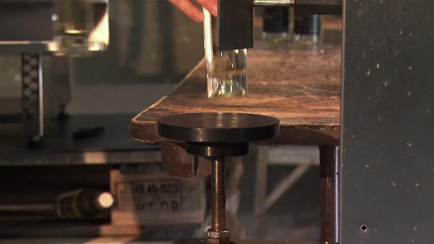A man loading ice wine bottles into a  hydraulic corking machine.