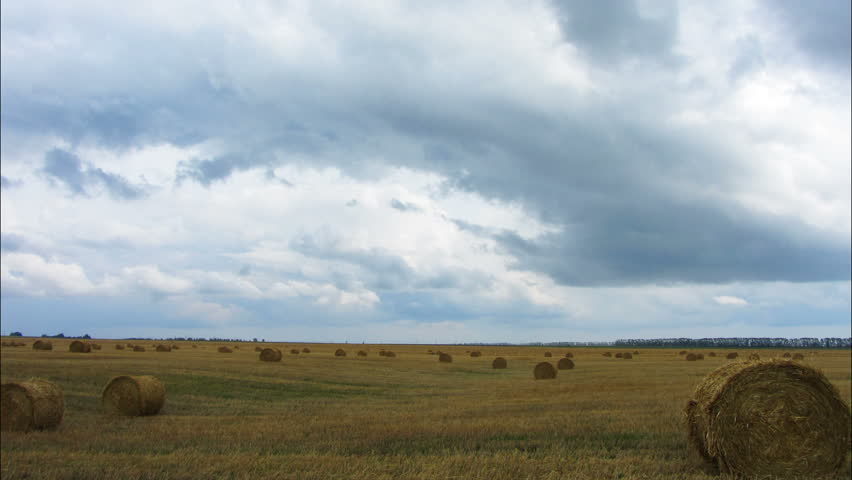 landscape with harvested bales of straw in field - timelapse 4k