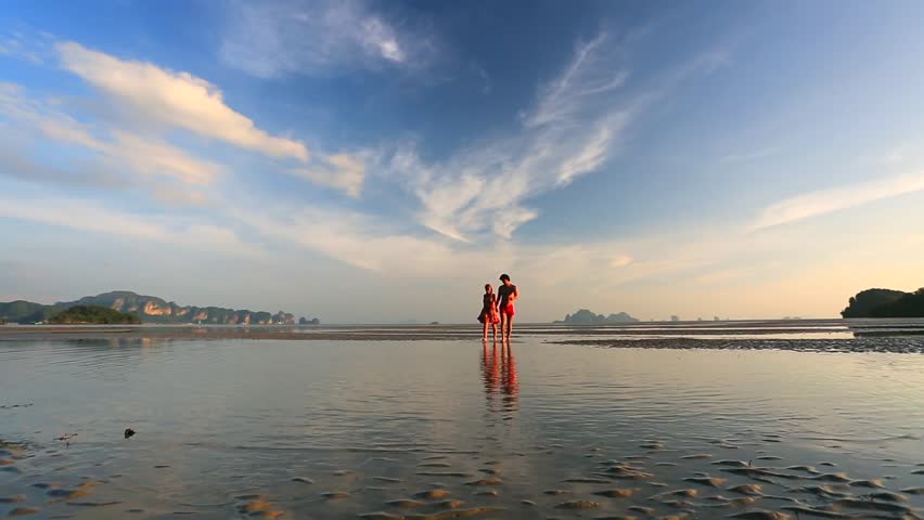 Young couple walking on a beach at sunset in Krabi, Thailand. Low tide.