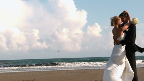 Beautiful newlywed couple hugging on the beach in slow motion