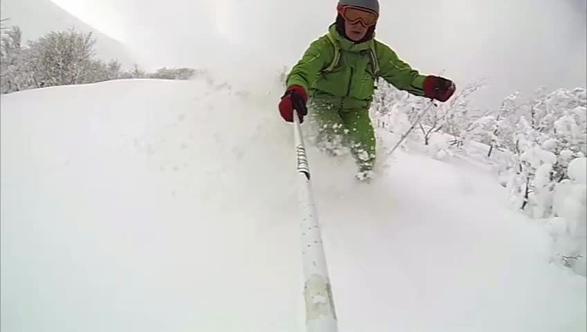 Skiing fast down a steep pitch in cold dry powder. Backlit snow highlights dry, cold, fluffy, snow quality as skier passes camera. slow motion. 