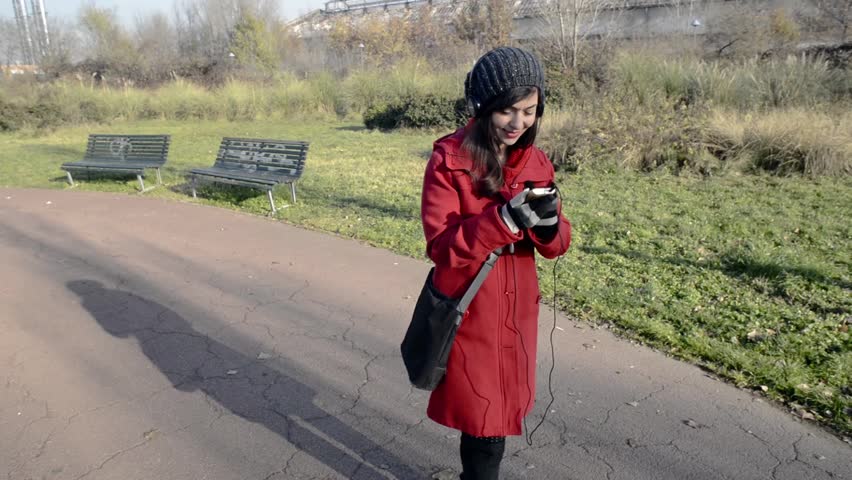 beautiful woman listening music headphones walking park