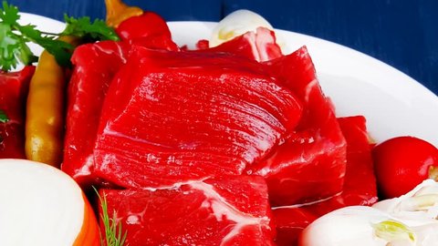 raw fresh beef meat slices in a white bowls with onion and red peppers serving on blue table with cutlery 1920x1080 intro motion slow hidef hd