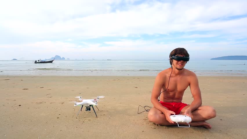 Seashore. Happy young man controlling quadcopter via video googles. Krabi,