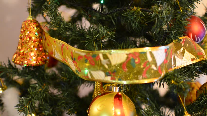 Putting ribbon ornament on Christmas tree, closeup