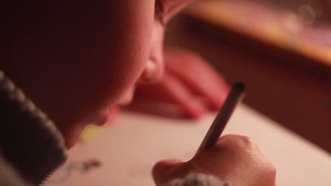 Boy draws a picture by candlelight. Turn off the electricity, global cataclysm
