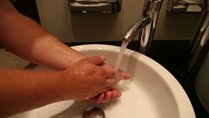 man washes his hands under tap