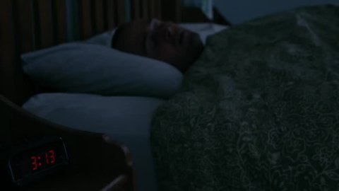 A man with insomnia having trouble sleeping late at night in his bed