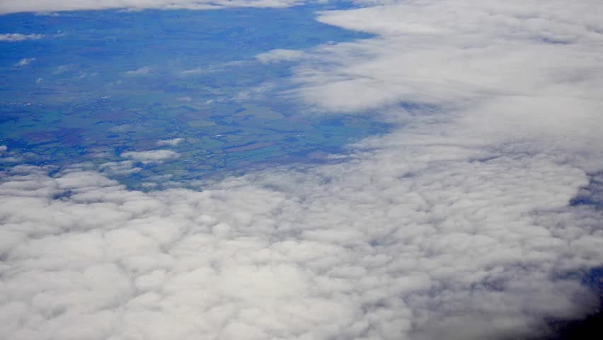 Aerial view of Europe out of an airplane window above the clouds with the earth