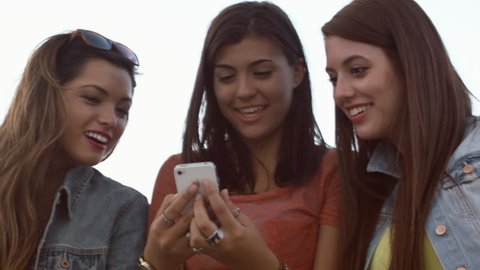 Teen Girls Amused By Something They See On A Cell Phone