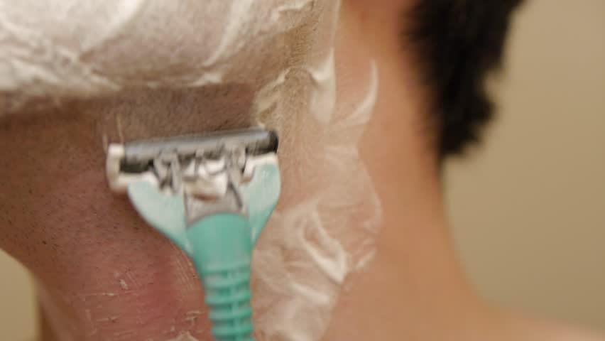 Man shaving his facial beard with a disposable manual razor.