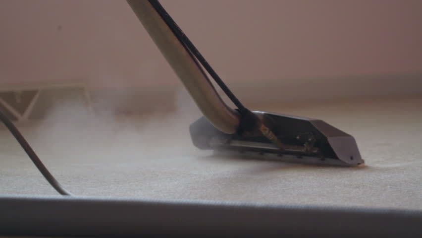 Detail of carpet being steam cleaned with a professional steam wand, power wash