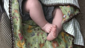 Video of a very young babies feet moving in a seat. Blankets and short pants. Rekindle Photo