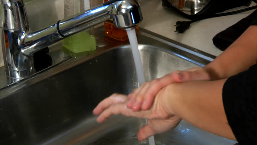 A woman washes her hands.