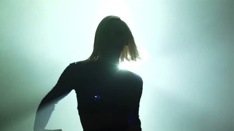 Slow-motion of a backlit go-go dancer running towards the camera and performing with passion