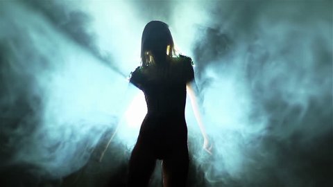 Backlit showgirl making a dramatic performance among smoke streams and beams o light