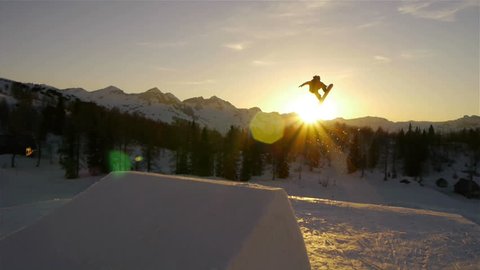 AERIAL: Snowboarder jumping over a kicker in snow park