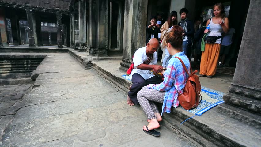 ANGKOR, CAMBODIA - CIRCA DECEMBER: Monk make good luck talisman for tourist on