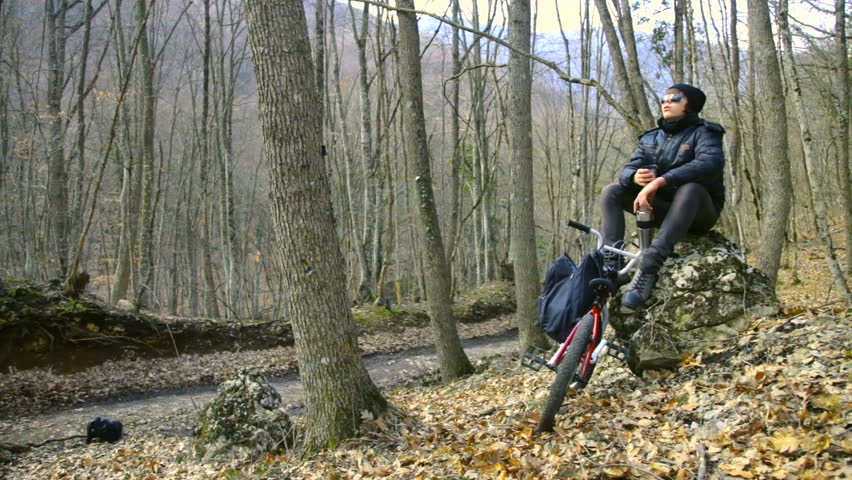 Teen on bike is resting in the autumn forest
