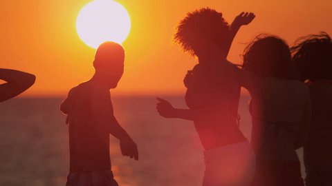 Happy male female college friends laughing dancing on beach at sunset on weekend break shot on RED EPIC, 4K, UHD, Ultra HD resolution