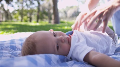 Happy smiling baby boy lying rug outdoors visit park playing big blue ball slow motion shot on RED EPIC, 4K, UHD, Ultra HD resolution