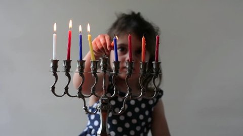 Jewish girl (female age 03-04) lit eight candles on Hanukkah menorah on the last day of Hanukkah Jewish holiday. Isolated on white background. Real people. Copy Space