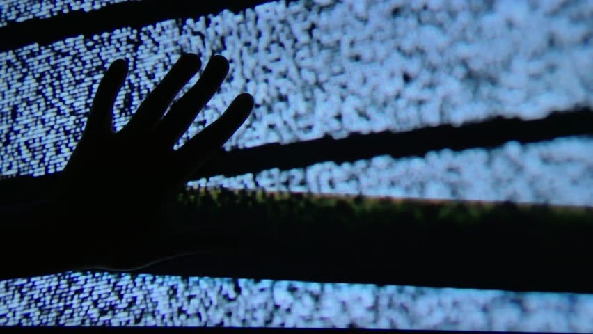 A mysterious hand touches the static on a television screen.
