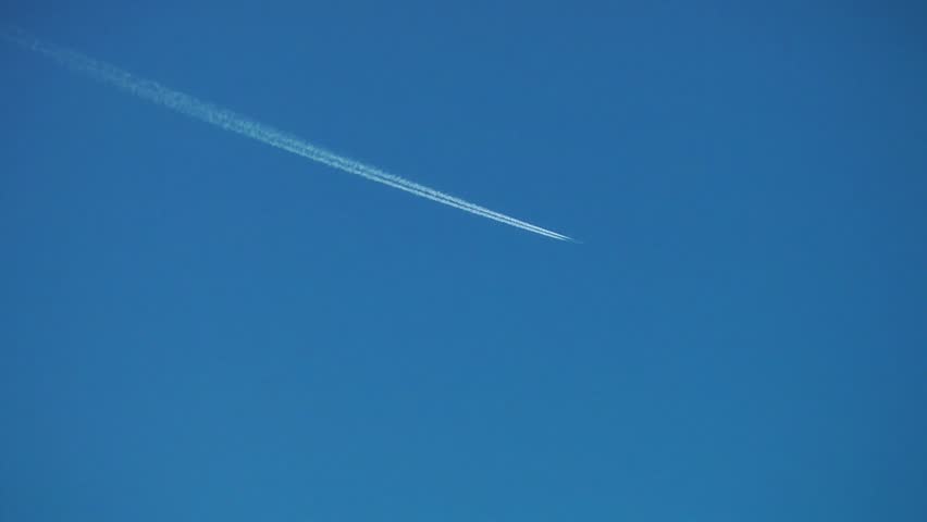 A Jet plane cuts across a perfectly clear blue sky, leaving a drifting vapor