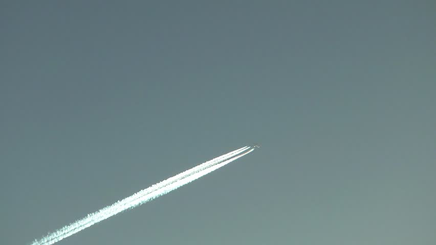 A Jet plane cuts across a perfectly clear sky, leaving a drifting vapor trail.
