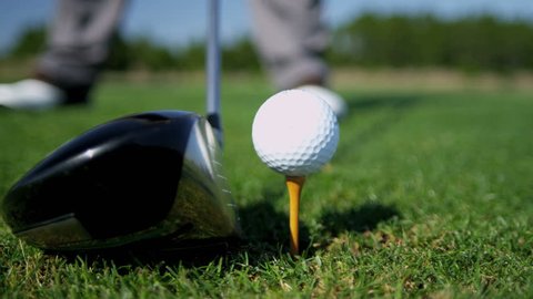 Close up ball on tee retired golfer taking swing hitting golf ball off tee on golf course feet only shot on RED EPIC, 4K, UHD, Ultra HD resolution