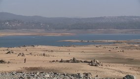 Drought low water in California Folsom lake reservoir with man an boat in distance HD  high definition stock video footage