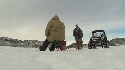 Men ice fishing winter mountain frozen lake HD. State tournament and contest for biggest Rainbow Trout caught from Scofield Lake central Utah. Wearing cold weather insulated clothes, gloves and hat.