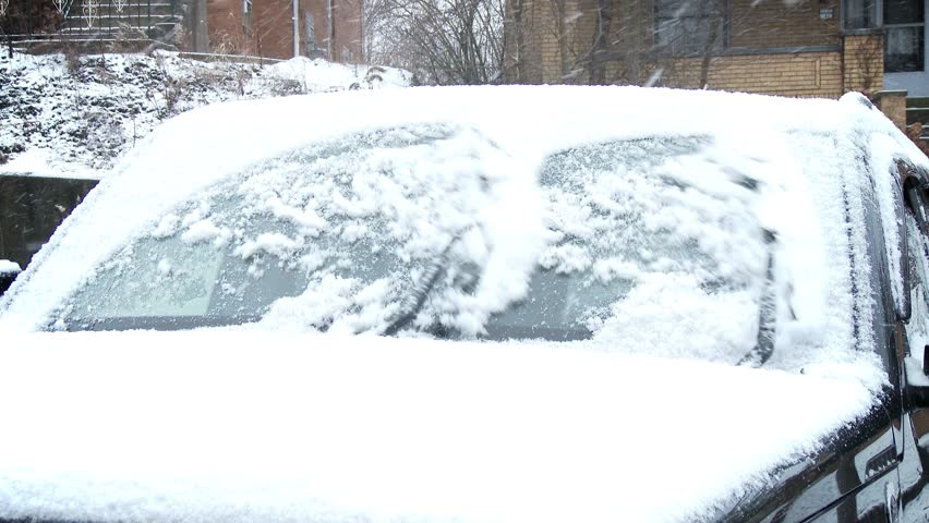 Windshield wipers brush away the snow from a car's windshield.